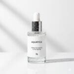 AI-generated product photo of an Aquatica Hydration Boost Super Serum dropper bottle with clean white label and silver chrome dropper cap against a white studio background with diagonal shadow light