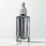 AI-generated product photo of a clear glass skincare serum dropper bottle with white cap and water droplets on a pure white studio background