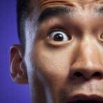 Extreme close-up of a man's face with a wide, shocked eye.
