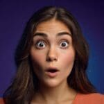 Close-up of a woman with freckles and long brown hair looking surprised.